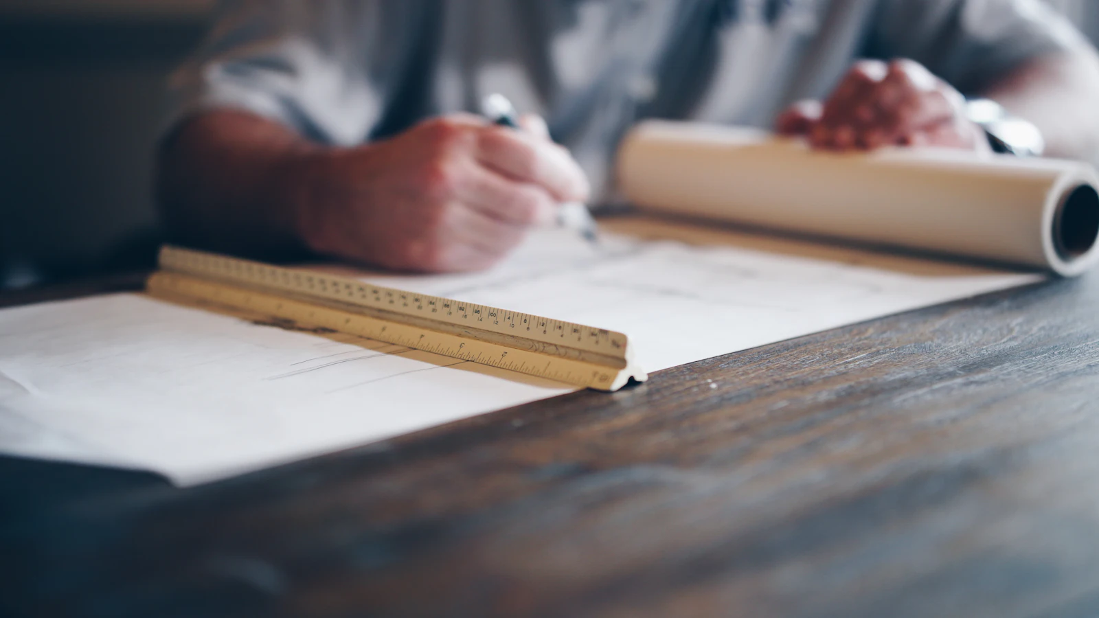 Architect drafting a plan with a pencil and scale rule